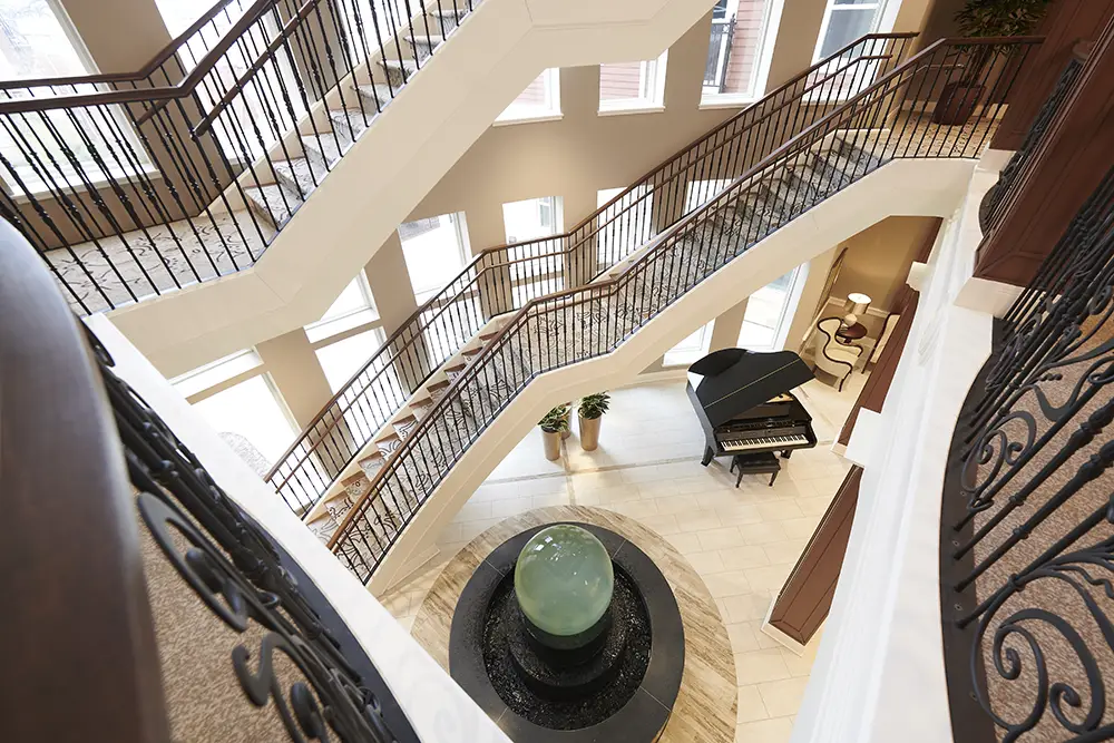 TWRH2 A view from an upper floor shows a spiral staircase, a black grand piano, a circular water fountain, and large windows in a spacious, well-lit lobby.