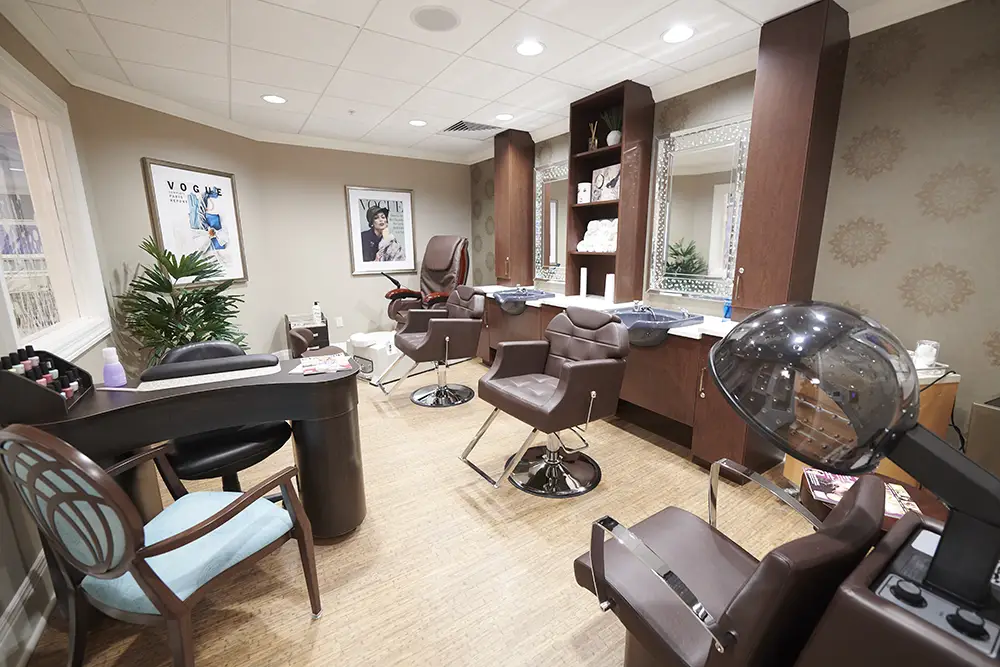 TWRH8 A modern hair salon with brown chairs, hair washing stations, a styling desk, large mirror, and hairdressing equipment under bright ceiling lights.