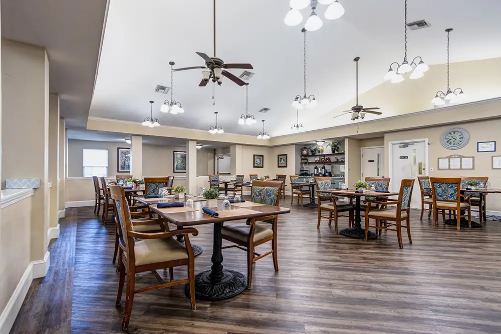 Spacious dining room with wooden tables and chairs, decorative plants, framed art on walls, and bright overhead lighting. Spacious dining room with wooden tables and chairs, decorative plants, framed art on walls, and bright overhead lighting.