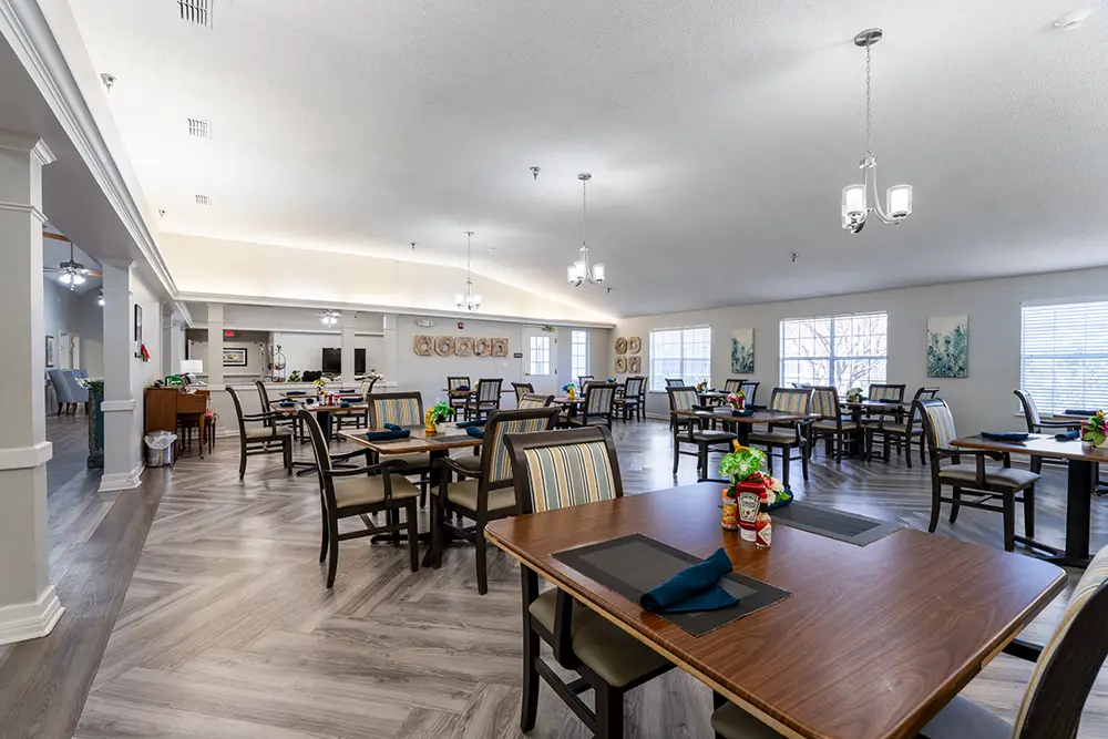 Spacious, well-lit dining room with multiple tables and chairs, large windows, wood flooring, and simple decor. Spacious, well-lit dining room with multiple tables and chairs, large windows, wood flooring, and simple decor.